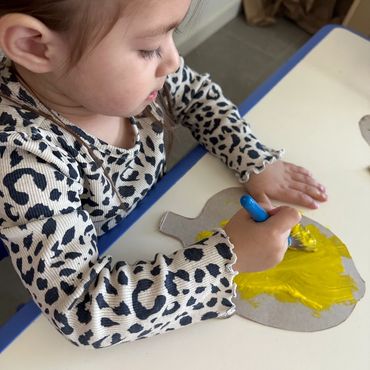 Little girl painting on cardboard 