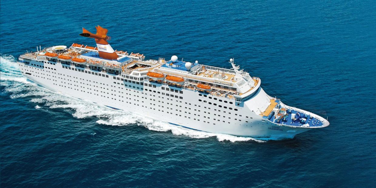 Large white cruise ship sailing on clear blue ocean waters.