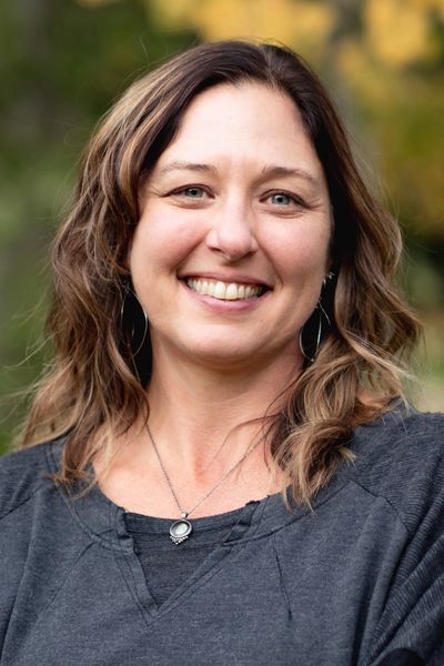 Smiling woman with shoulder-length hair outdoors.