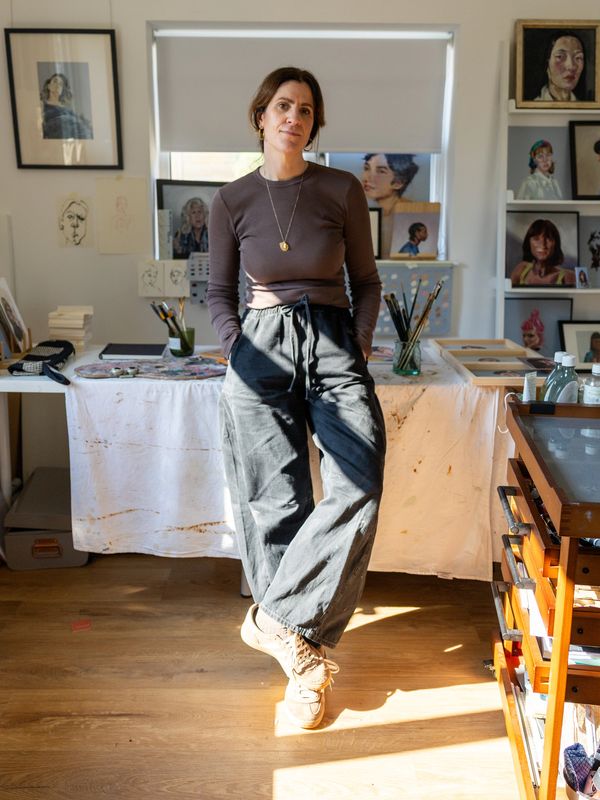 Artist standing confidently in her bright, art-filled studio.