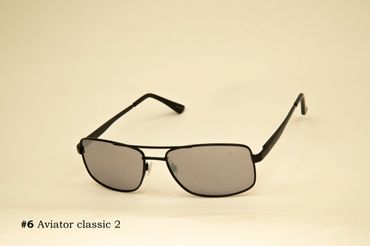 Black aviator classic sunglasses with tinted lenses on a beige background.