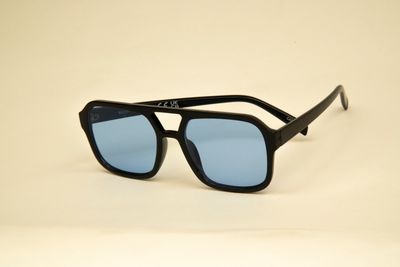 Stylish black sunglasses with blue tinted lenses on a beige background.