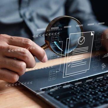 Person using magnifying glass to examine digital documents on a laptop.
