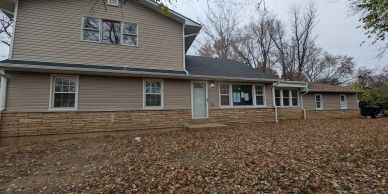 Two-story suburban house with fallen leaves in yard.