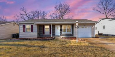 Single-story house with a garage and front yard at sunset.