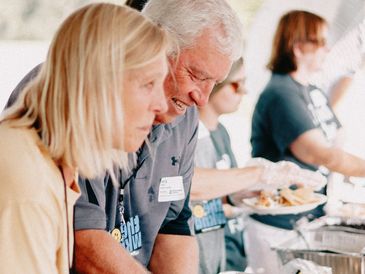 People serving food at an event.