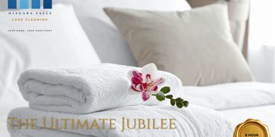 Freshly folded white towels with a pink orchid on a pristine bed.