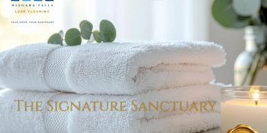 Stacked white towels with a candle and eucalyptus for a spa-like ambiance.