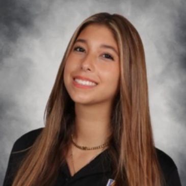 Young woman with long hair smiling against a gray background.