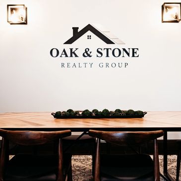 Oak & Stone Realty Group conference room in Cosmopolis, WA, with logo sign between two lights