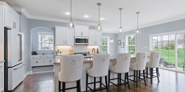 Interior photo of modern luxury kitchen with white cabinets, white appliances, and breakfast bar. 