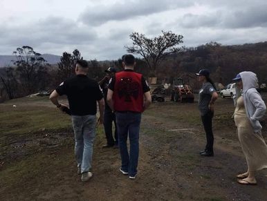 Group of people standing outdoors on a cloudy day in a rural area.