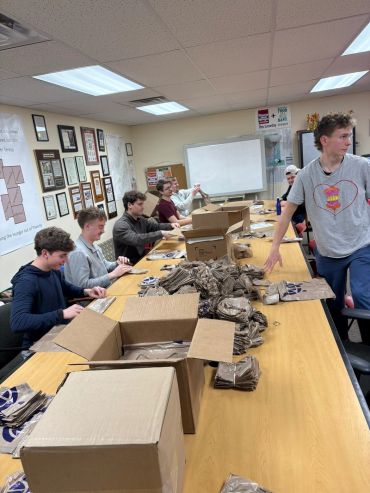 Group of young people packing items in a classroom.