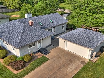 A gray house with a detached garage and green surroundings.