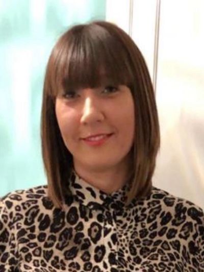Woman with straight brown hair and leopard print shirt smiling.