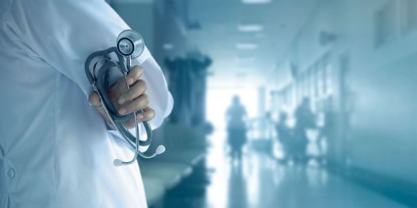 Doctor holding a stethoscope in a hospital corridor.