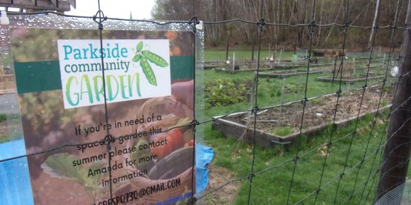 Community garden sign inviting people to contact for summer garden space.