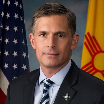 Portrait of Martin Heinrich New Mexico U.S. Senator with American and New Mexico flags.