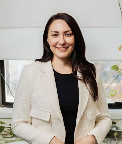 A smiling woman in a white blazer and black top.
