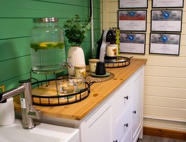 Cozy kitchen corner with infused water dispenser and coffee machine on wooden countertop.
