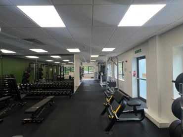 Spacious gym with various fitness equipment and mirrors.