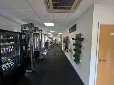 Interior gym hallway with workout equipment and vending machine.