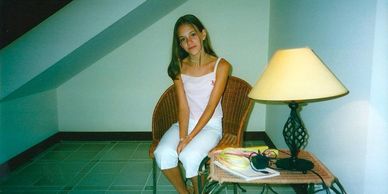 Young woman sitting on a wicker chair in a simple room.