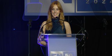 A woman speaking at a podium during an event with a 50th anniversary logo.