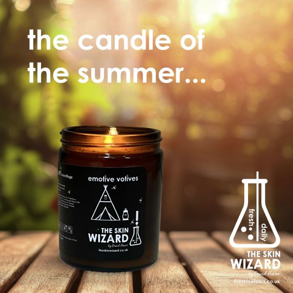 The Skin Wizard summer candle glowing warmly on a wooden table.