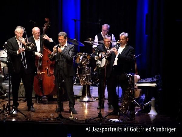 A jazz band performing on stage with various instruments under blue lighting.
