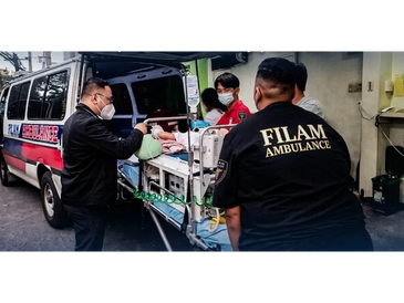 Medical workers transporting a patient into a FILAM ambulance.