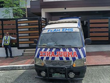 Front view of a parked ambulance with a security guard standing nearby.
