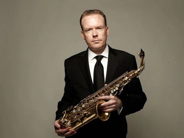 Man in a suit holding a saxophone.