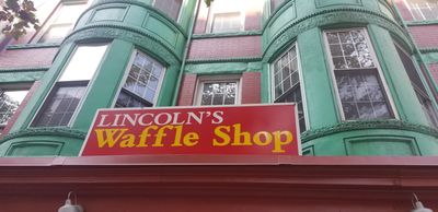 Sign for Lincoln's Waffle Shop on a building with green bay windows.