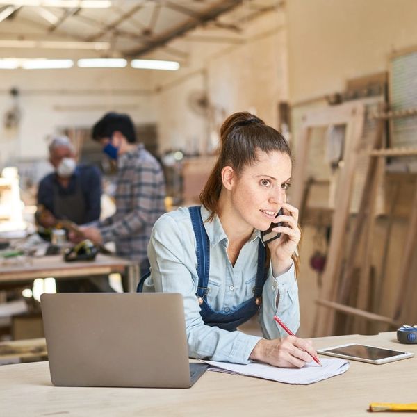 Craftswoman talking to phone booking a woodworking workshop