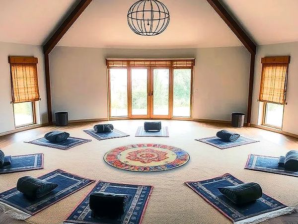 A serene meditation room with cushions arranged in a circle around a colorful rug.