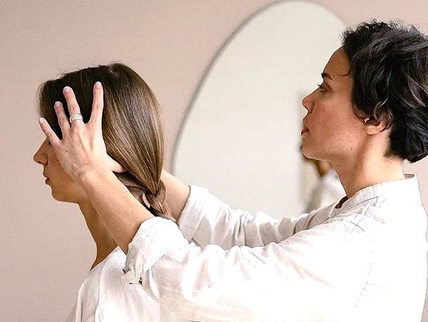 A person styling another's hair in a calm, indoor setting.