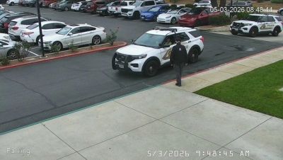 Police officer near patrol car in parking lot.