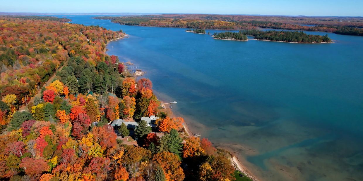 Aerial view of a lake surrounded by vibrant autumn foliage.