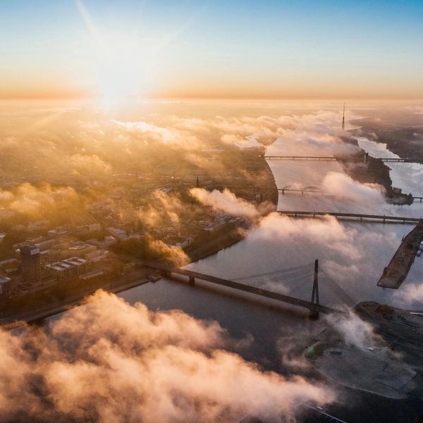 Sunrise over a river with multiple bridges partly covered by clouds.