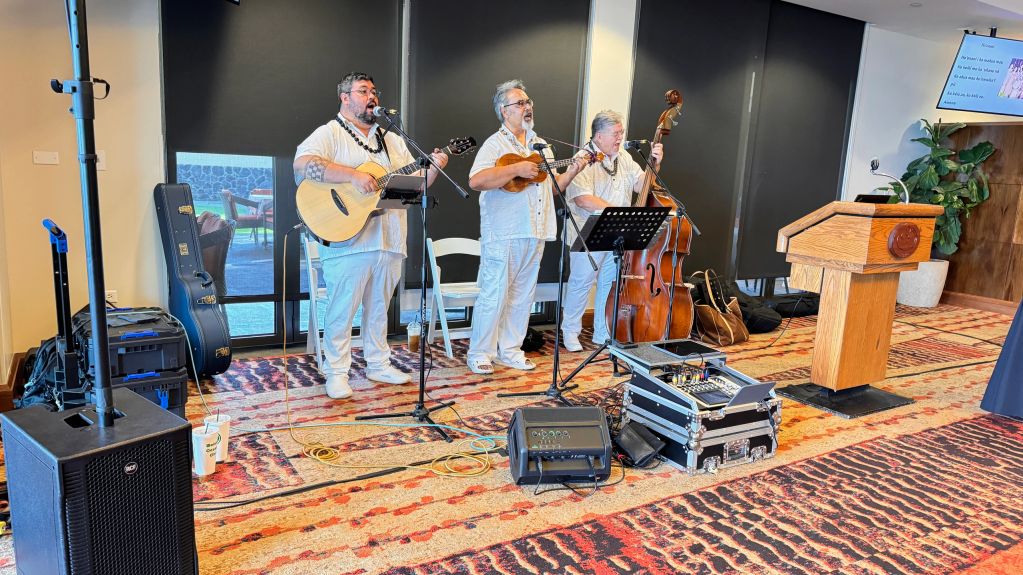Three men playing music with string instruments indoors.