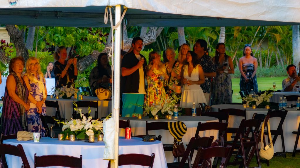 Group of people gathered under a tent at an outdoor event.
