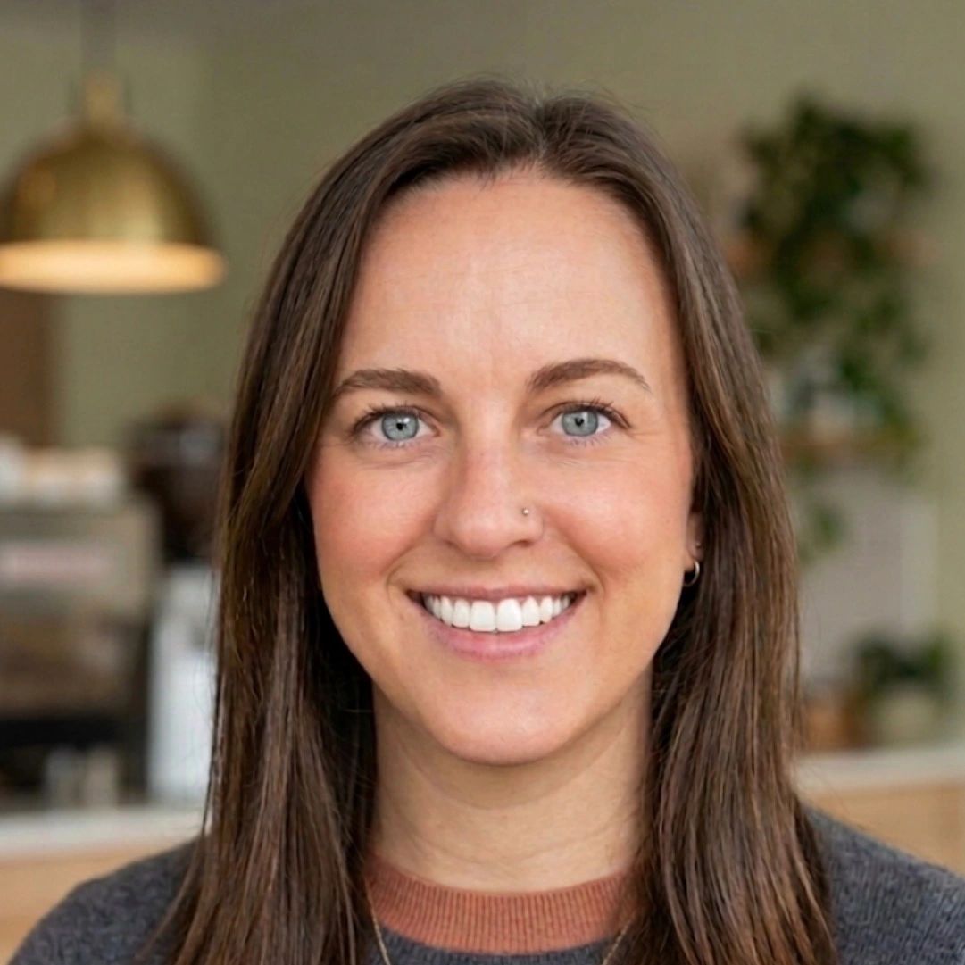 Smiling woman with blue eyes and long brown hair in a cozy indoor setting.