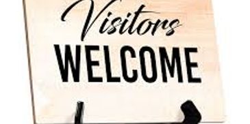 A wooden sign with the words 'Visitors Welcome' in black letters.