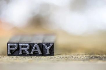 Metal letters spelling 'PRAY' in a shallow focused setting.