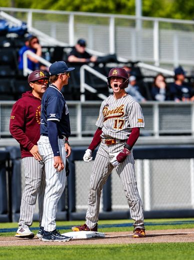 Baseball player celebrates intensely at first base during a game.