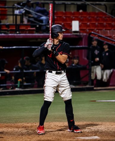 Baseball player poised to bat during nighttime game.