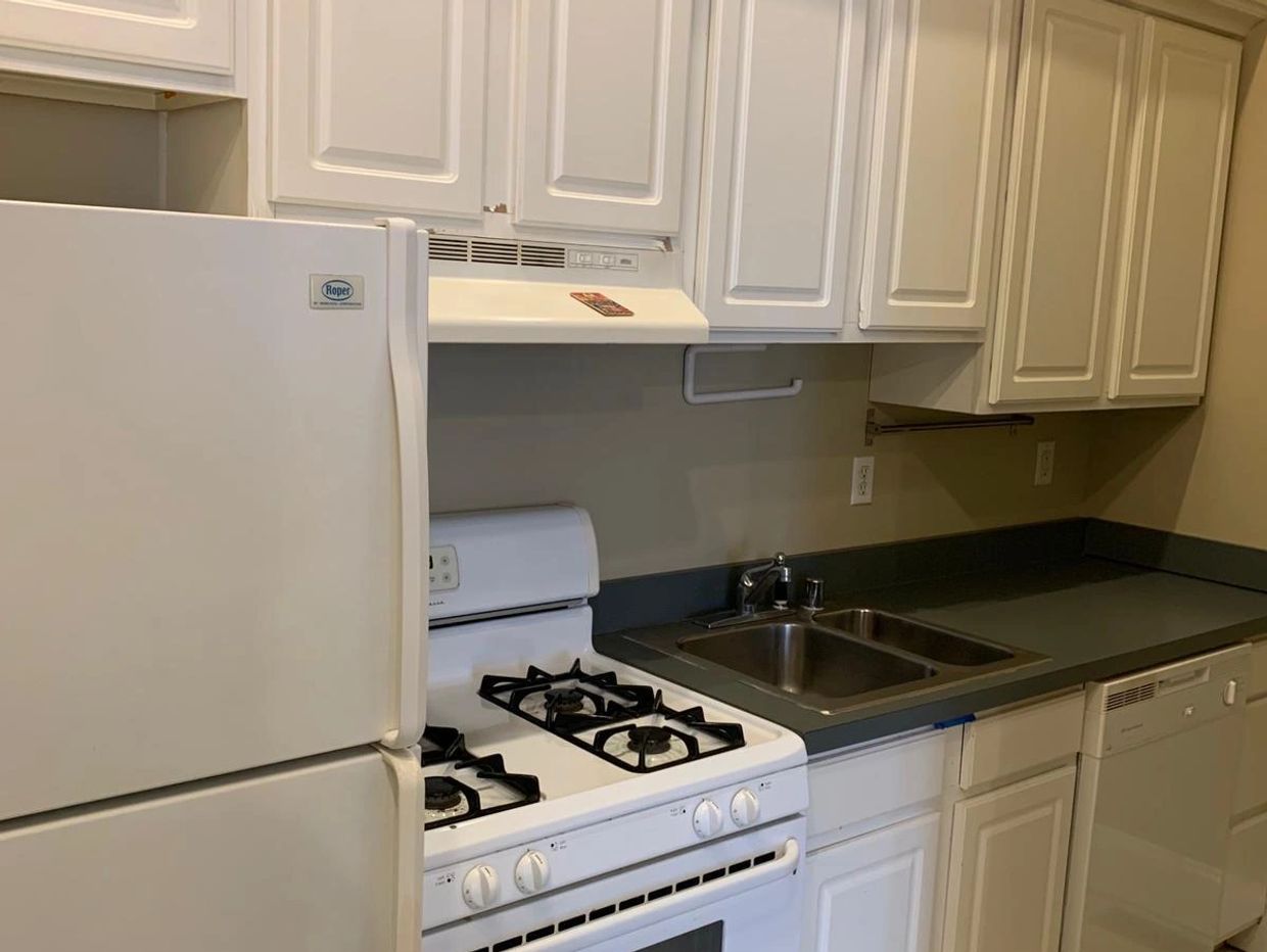 Clean kitchen with white cabinets and appliances including stove, refrigerator, and dishwasher.
