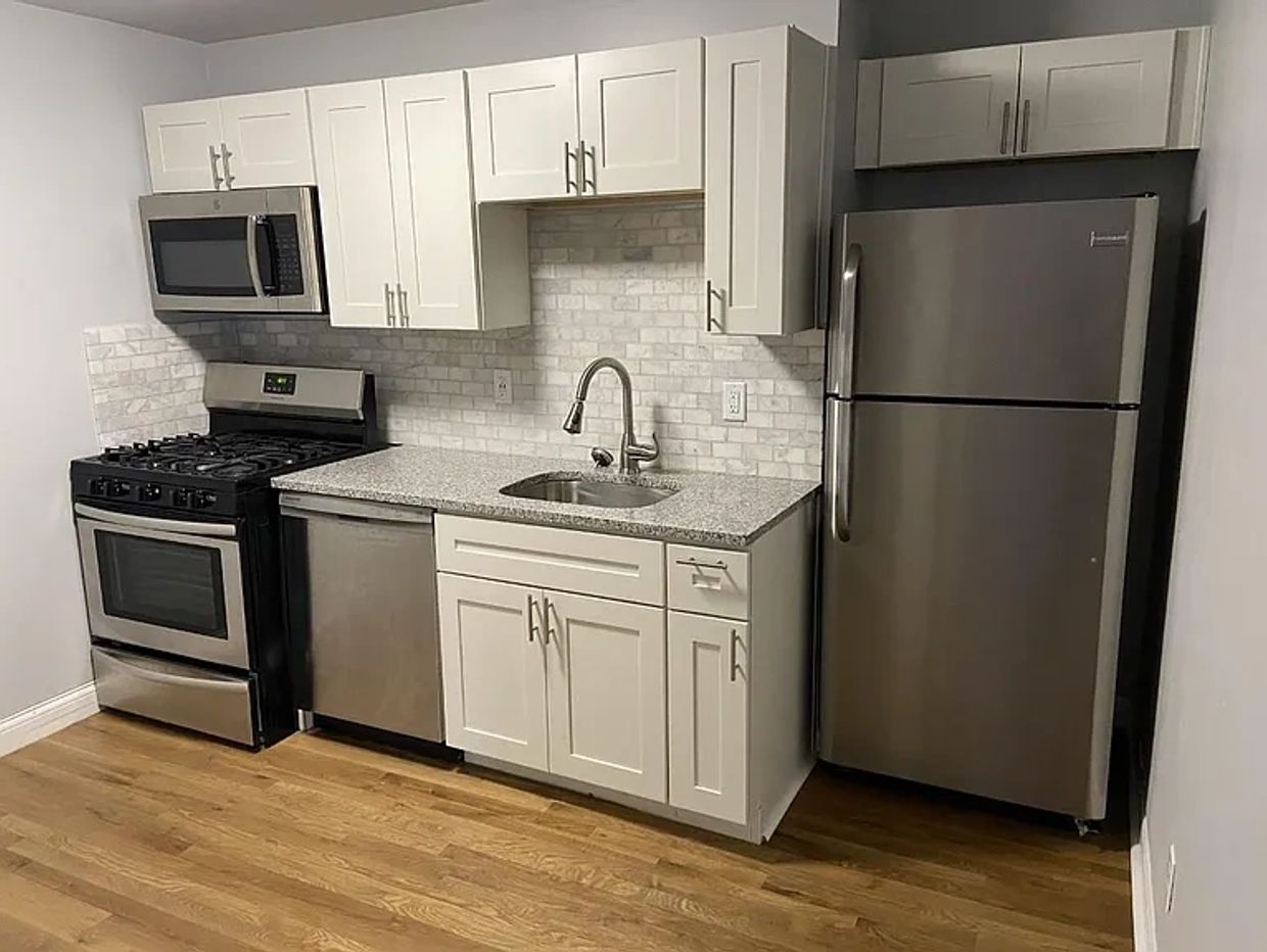 Modern kitchen with stainless steel appliances and white cabinetry.