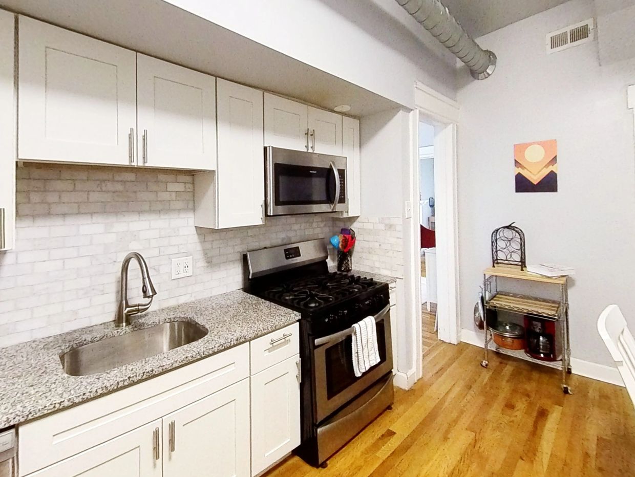 Modern kitchen with white cabinets, granite countertops, and stainless steel appliances.